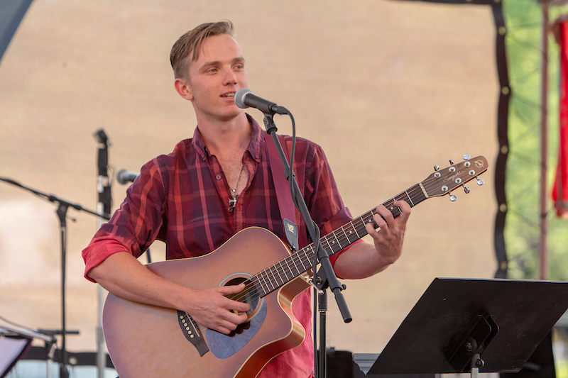 Young man playing guitar on stage.